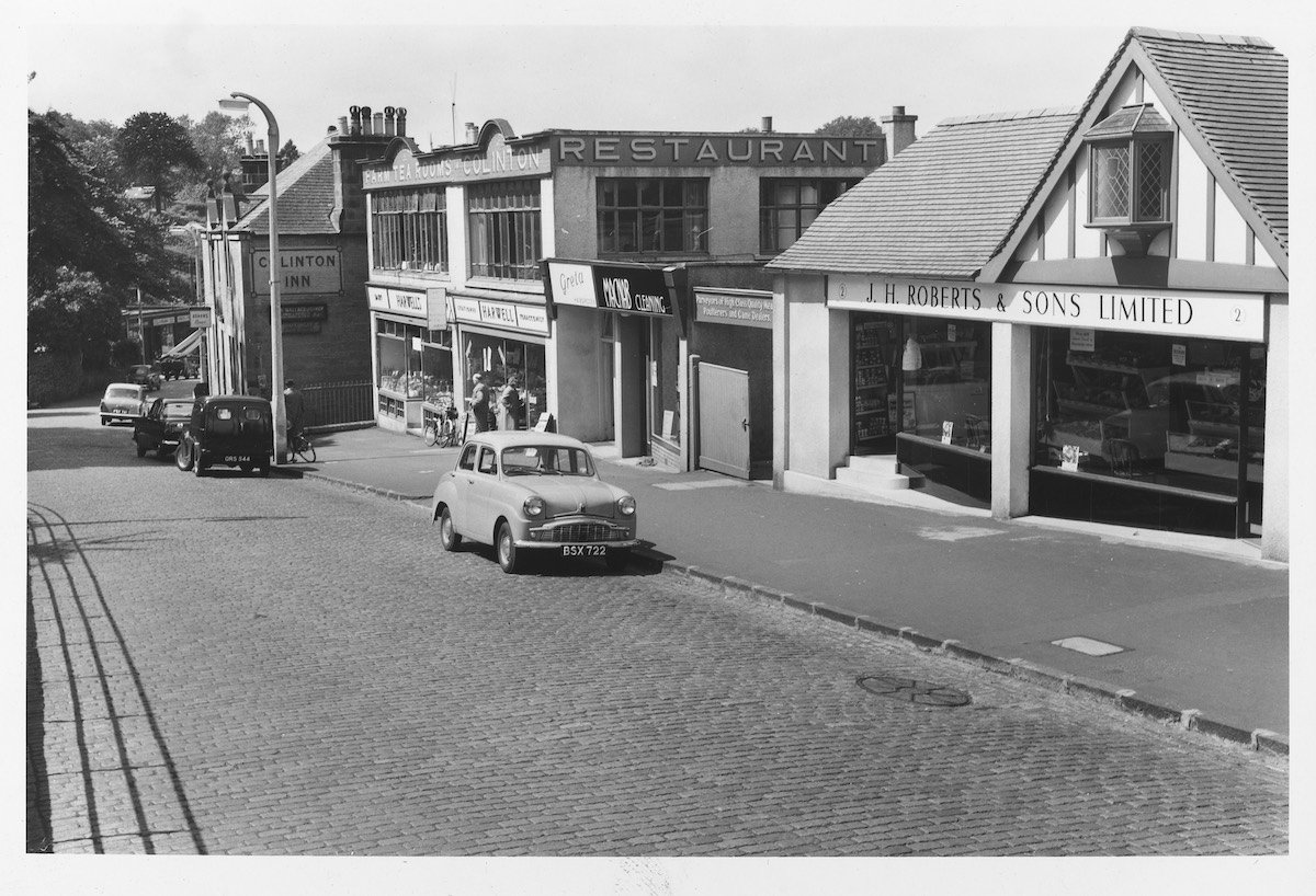 A quiet street in a Colinton with stone buildings, and shops